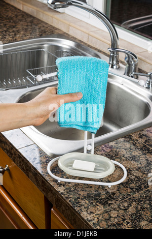 Female hand hanging microfiber dish towel on rack in kitchen Stock Photo