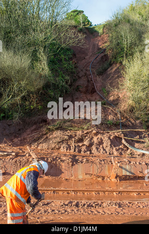 Teignmouth, Devon, England. December 24th 2012. A landslide at the Teignmouth to Dawlish railway line with a railway workman. Stock Photo