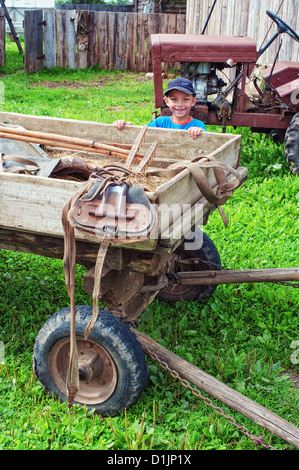 Portrait of the little boy on the rural street near a cart. Stock Photo