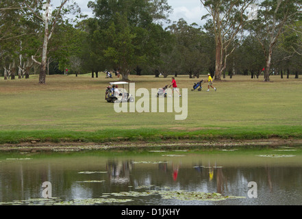 Golfers with golf buggy beside the lagoon at golf course beside Ululah lagoon at Maryborough Stock Photo
