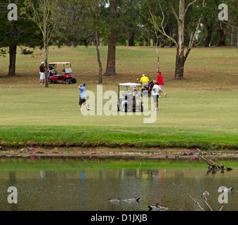 Golfers with golf buggy / cart beside the lake at golf course at Maryborough Australia Stock Photo