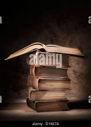 Old books stacked, with one open book on top. Stock Photo
