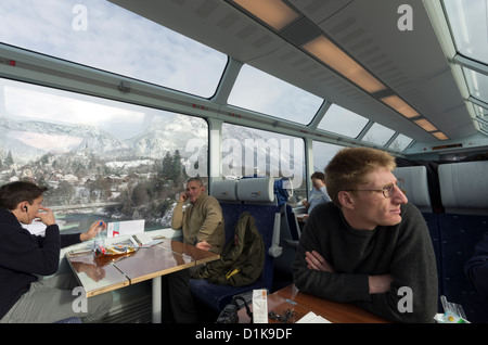 Passengers on the Glacier Express Train look out onto the mountains near Brig, Switzerland. Stock Photo