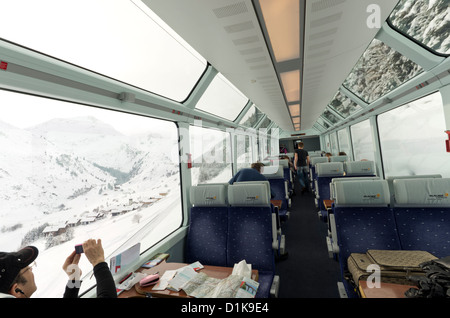 Passengers on the Glacier Express Train look out onto the mountains near Oberwald, Switzerland. Stock Photo
