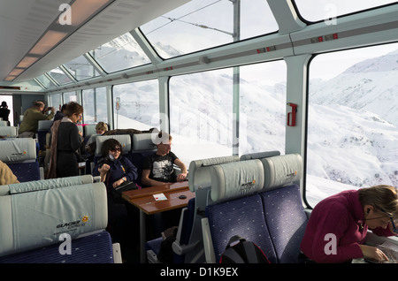 Passengers on the Glacier Express Train look out onto the mountains near Andermatt, Switzerland Stock Photo