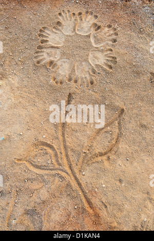 Hand prints in a circular pattern on a dirt track made into a flower