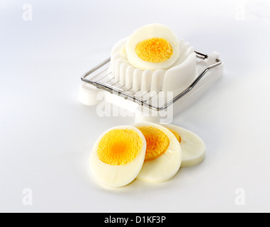 An white egg slicer with half an egg and a few slices in front Stock Photo