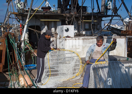 Biloxi, Mississippi - Shrimp fishermen work on their nets while docked on Biloxi's Back Bay. Stock Photo