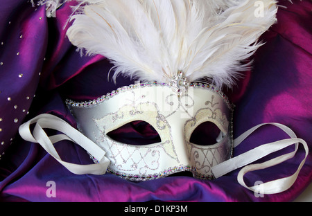 A mardi gras masquerade ball mask on a dress made from purple satin Stock Photo