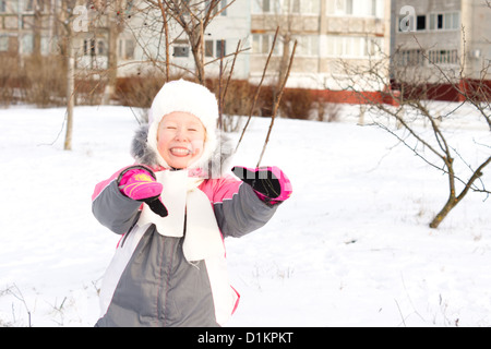 Merry little girl playing in the snow laughing as she enjoys herself on a cold winter day, with copyspace Stock Photo