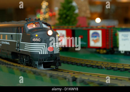 Dec. 26, 2012 - Garden City, New York, U.S. - The Long Island Garden Railway Society large-scale model train display is a festive winter holiday attraction in the vast 3-floor atrium of Cradle of Aviation museum. This G-scale New York Central train passes by colorful train cars as it goes along curve in the tracks. LIGRS shares the knowledge, fun, and camaraderie of large-scale railroading both indoors and in the garden, and is family oriented. Stock Photo