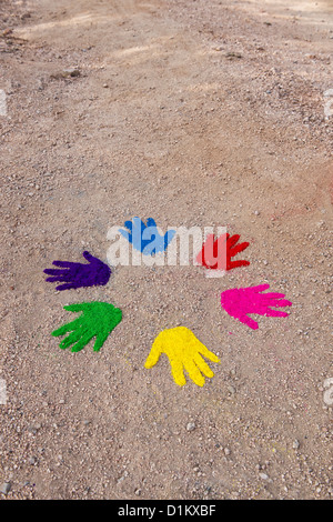 Coloured powder hand prints in a circular pattern on a dirt track Stock Photo