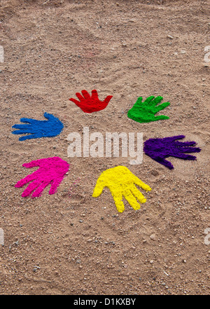 Coloured powder hand prints in a circular pattern on a dirt track Stock Photo