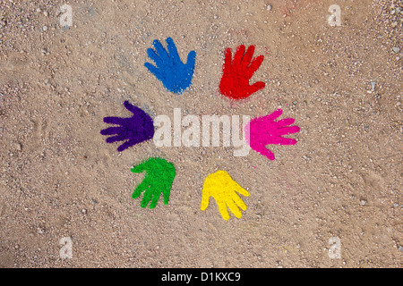 Coloured powder hand prints in a circular pattern on a dirt track Stock Photo