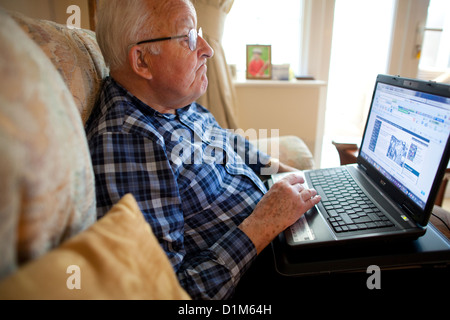 Elderly man using a laptop computer at home Stock Photo