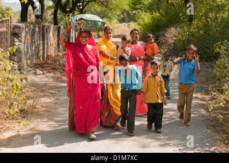 A happy smiling colorful Indian family group of women boys girls and a baby return from shopping on a quiet road in India Asia Stock Photo