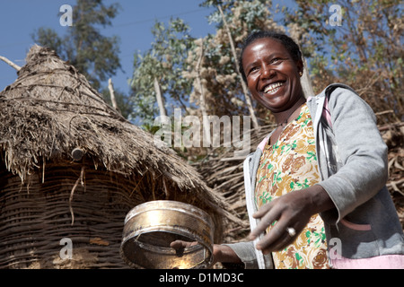 A woman winnows tef grain outside her home in Ankober, Ethiopia. Stock Photo