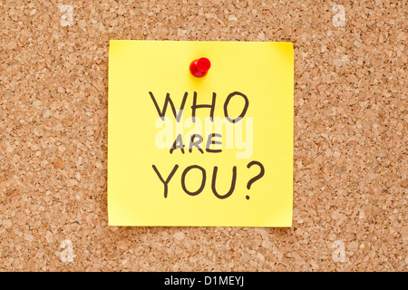 Who Are You written on an yellow sticky note pinned on a cork bulletin board. Stock Photo