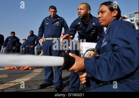 Boatswain’s Mate 2nd Class Brittany Hargrove handles a fire hose as Chief Gas Turbine System Technician (Electrical) Timothy Ward, center, directs her and Chief Boatswain’s Mate Aaron Stewart observes during damage control Olympics aboard the guided-missile destroyer USS Jason Dunham (DDG 109). Jason Dunham is deployed to the U.S. 5th Fleet area of responsibility conducting maritime security operations, theater security cooperation efforts and support missions for Operation Enduring Freedom..ARABIAN SEA (Dec.29, 2012) US Navy Photo Stock Photo