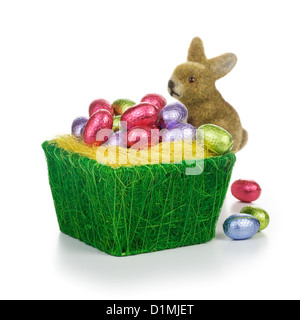 Bunny and basket full of chocolate Easter eggs wrapped in foil on white background Stock Photo