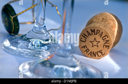 Champagne cork on white tablecloth with glasses wire retaining frame and cap Stock Photo