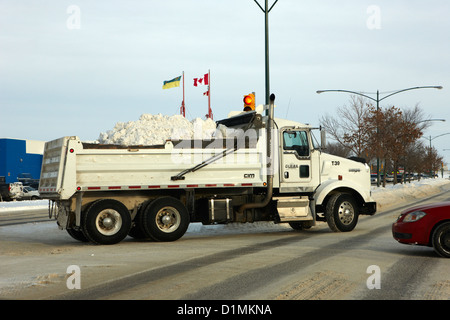 municipal city dump truck taking away snow cleared from parking lots and roads in Saskatoon Saskatchewan Canada Stock Photo