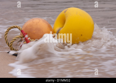 Yellow and orange mooring buoys in surf. Stock Photo