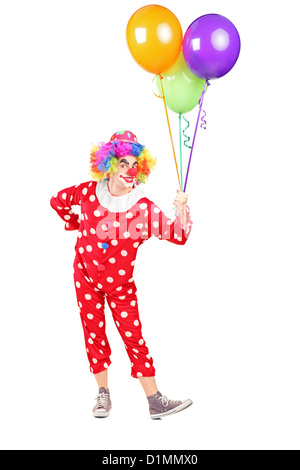 Full length portrait of a male clown in costume holding bunch of balloons isolated on white background Stock Photo