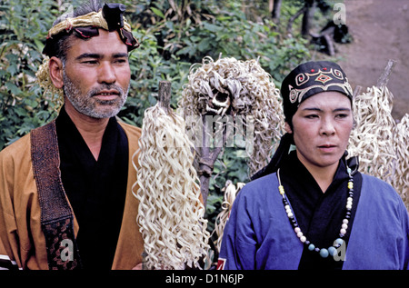 A bearded Ainu man and his wife in traditional dress pose with a bear’s skull in an Ainu graveyard in 1962 on the island of Hokkaido in northern Japan. Stock Photo