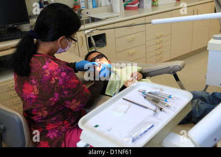 Dental nurse performing fluoride therapy on toddler boy patient Stock Photo