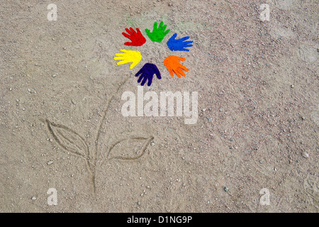Coloured powder hand prints in a circular pattern made into a flower on a dirt track Stock Photo