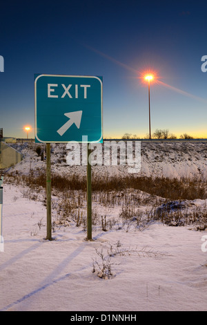 Highway Exit Sign In Winter At Dawn With Light Post Stock Photo