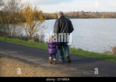 Grandfather with grandchild walking outdoors by a lake in winter Stock Photo