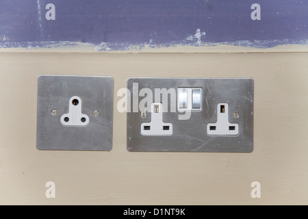 Old 'round pin' electrical / electricity socket (left) for lights / lamps, and modern sockets for square 3 pin plug / plugs. UK. Stock Photo