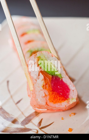 A sushi roll with pink rice paper, tuna, salmon and avocado. Stock Photo