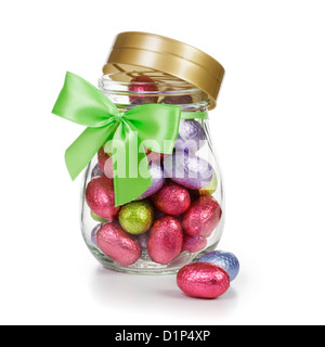 Open glass jar full of chocolate candy Easter eggs wrapped in foil and decorated with bow clipping path included Stock Photo