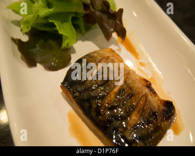Fish steak with green vegetables on white dish. Stock Photo