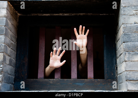 Two hands stretch out from cells looking for freedom Stock Photo