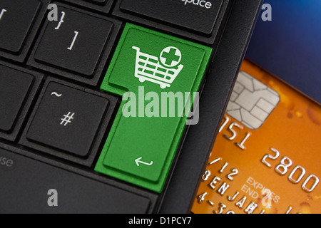 Add to Cart Enter Key on a modern laptop qwerty keyboard with bank smart card underneath to represent online shopping Stock Photo