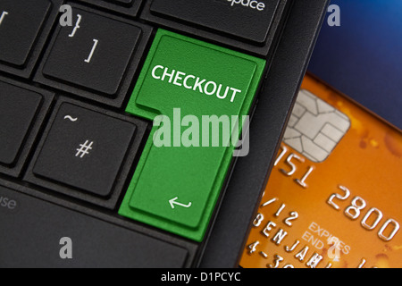 Checkout Enter Key on a modern laptop qwerty keyboard with bank smart card underneath to represent online shopping Stock Photo