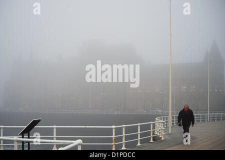 Aberystwyth Wales UK,. Wednesday 2 January 2013.  A man walking in the mist on the promenade with the university Old College building in the background. After weeks of rains and storms, the new year brings thick mists and seafog to Aberystwyth , on the west Wales coast.   Photo Credit: keith morris/Alamy Live News