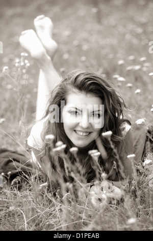20 year old woman lying down on the grass, black and white image. Stock Photo