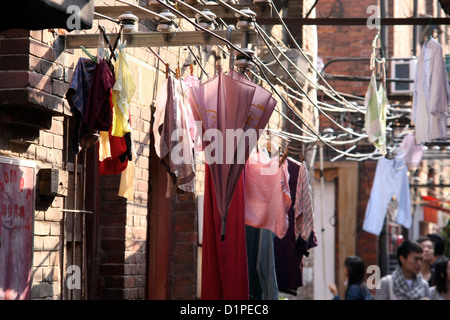 Washing hangs from clothes lines above alleyways in central Shanghai Stock Photo