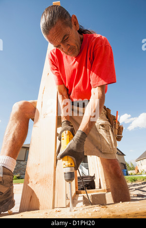Hispanic man using drill on construction site Stock Photo