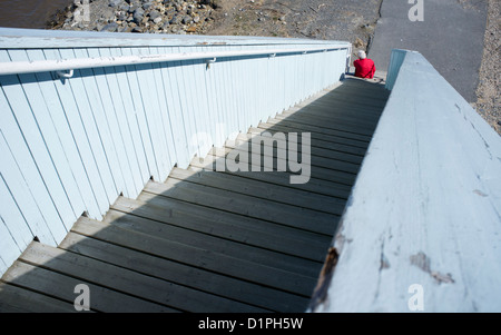 Elderly woman sitting at the bottom of wooden stairs , Finland Stock Photo