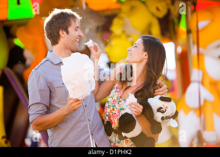 Caucasian couple sharing cotton candy at carnival Stock Photo