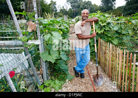 Black man leaning on shovel in community garden Stock Photo - Alamy