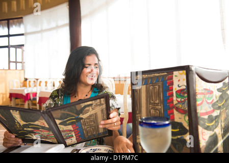 Hispanic woman looking at restaurant menu Stock Photo