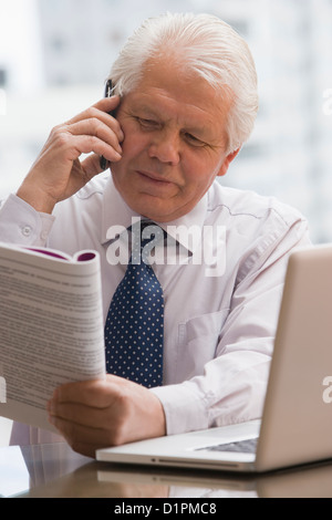 Chilean businessman reading report and talking on cell phone Stock Photo