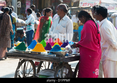 South Indian woman selling coloured powder used for making rangoli designs at festivals from a cart on the street. Andhra Pradesh, India Stock Photo